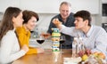 Happy young guy concentrating on removing block from tower while playing jenga, spending free time with girl-friend or Royalty Free Stock Photo