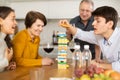 Happy young guy concentrating on removing block from tower while playing jenga, spending free time with girl-friend or Royalty Free Stock Photo