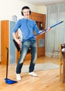 Happy young guy with dustpan and brush