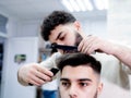 Happy young guy getting a haircut by a professional male hairdresser in a barbershop Royalty Free Stock Photo