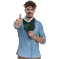 Happy young guy reading book and making thumbs up sign Royalty Free Stock Photo