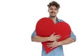 Happy young guy smiling and holding big red heart Royalty Free Stock Photo