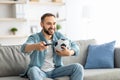 Happy young guy watching soccer game on TV, holding remote control and ball at home Royalty Free Stock Photo