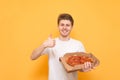 Happy young guy on a yellow background with a box of pizza in his hands,looking camera and showing finger up.Smiling man in a Royalty Free Stock Photo