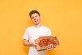 Happy young guy on a yellow background with a box of pizza in his hands looking into the camera and smiles. Young man wearing a Royalty Free Stock Photo