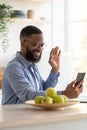 Happy young handsome african american businessman with beard in glasses waving hand at smartphone Royalty Free Stock Photo