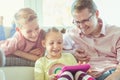 Happy young handsome father having fun with his two cute children playing with tablet Royalty Free Stock Photo