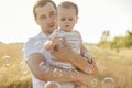 Happy young father hold and hug his baby boy at sunlight on field at summer day Royalty Free Stock Photo