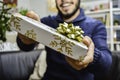 Happy young handsome man holding and giving a gift to someone