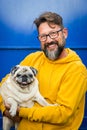 Happy young handsome man smile and hold his own old dog pug - cheerful people and animals lifestyle - caucasian male with beard Royalty Free Stock Photo