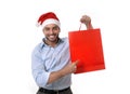 Happy young handsome man wearing santa hat holding red shopping bag Royalty Free Stock Photo