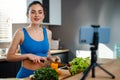 Happy young healthy woman influencer preparing fresh salad