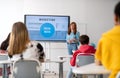 Young High school teacher giving marketing lesson to students in classroom Royalty Free Stock Photo
