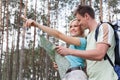 Happy young hiking couple holding map with woman pointing away in forest Royalty Free Stock Photo