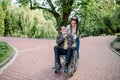 Happy young hipster modern woman with dreadlocks, walking together with her old senior grandfather, sitting in a Royalty Free Stock Photo