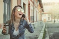 Happy young hipster woman walking on the street, using her smartphone and drinking coffee Royalty Free Stock Photo