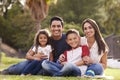 Happy Young Hispanic Family Sitting The On Grass In The Park Smiling To Camera, Close Up