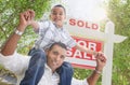 Happy Young Hispanic Father and Son In Front of Sold For Sale Real Estate Sign Royalty Free Stock Photo
