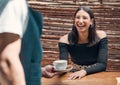 Happy young hispanic woman receiving a cup of coffee from a waiter in a local cafe. Mixed race woman excited to be Royalty Free Stock Photo