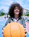 Happy young hispanic woman about to workout holding a basketball while standing on a court. Portrait of smiling girl Royalty Free Stock Photo