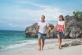 Happy young honeymoon couple walking on the beach. Ocean, tropical vacation on Bali island, Indonesia.