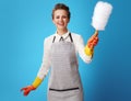 Happy young housemaid using dust cleaning brush on blue