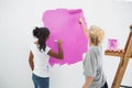 Happy young housemates painting wall pink Royalty Free Stock Photo