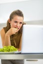 Happy young housewife eating grape and looking in laptop Royalty Free Stock Photo