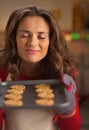 Happy young housewife enjoying smell of christmas cookies on pan Royalty Free Stock Photo