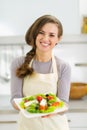 Happy young housewife giving fresh salad