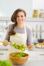 Happy young housewife mixing vegetable salad