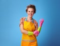 Happy young housewife pulling on rubber glove on blue Royalty Free Stock Photo