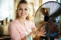 Happy young housewife showing metallic floor standing fan Royalty Free Stock Photo