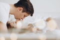 Happy young husband kissing his smiling pregnant wife lying on white bed and hugging baby belly bump. Stylish pregnant couple in Royalty Free Stock Photo