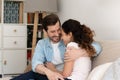 Young couple house buyers cuddle on couch enjoy new home