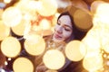 Young imaginative woman holding fairy lights in bokeh at Christmas market