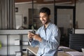 Happy young Indian businessman in casual typing message on cellphone Royalty Free Stock Photo