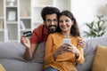 Happy young indian couple using smartphone and credit card at home Royalty Free Stock Photo
