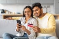 Happy young indian couple using smartphone and credit card at home Royalty Free Stock Photo