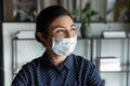 Happy young indian female manager in protective mask looking away.