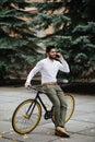 Happy young indian man talking on his cellphone in the city with fixed bicycle Royalty Free Stock Photo