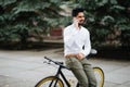 Happy young indian man talking on his cellphone in the city with fixed bicycle Royalty Free Stock Photo