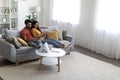 Happy Young Indian Spouses Relaxing With Modern Gadgets On Couch At Home Royalty Free Stock Photo