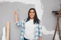 Happy young Indian woman holds up wrench during home DIY project renovations