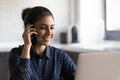 Smiling Indian woman work on laptop talking on cell Royalty Free Stock Photo