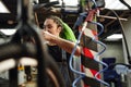 Positive young female mechanic checking bike in garage Royalty Free Stock Photo