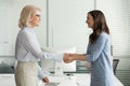 Happy young intern get hired rewarded handshaking female old boss Royalty Free Stock Photo