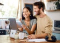 Happy young interracial couple calculating their budget using wireless devices at home. Smiling young caucasian man Royalty Free Stock Photo