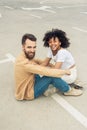 happy young interracial couple smiling at camera while sitting together Royalty Free Stock Photo