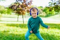 Happy young kid listening to music outdoor in a park. smiling little child dancing outside in a garden wearing headphones and